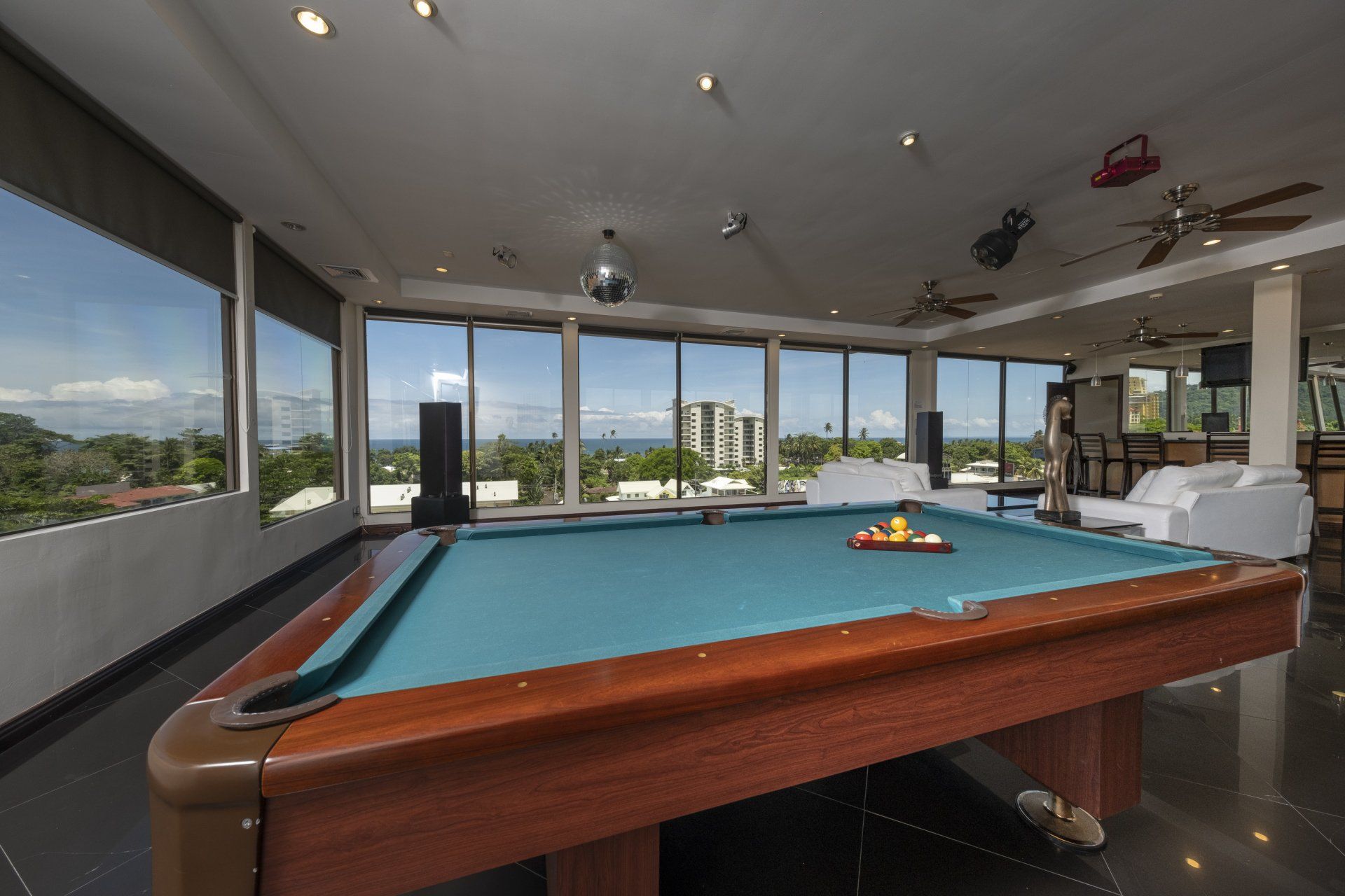 A pool table in a large room with lots of windows