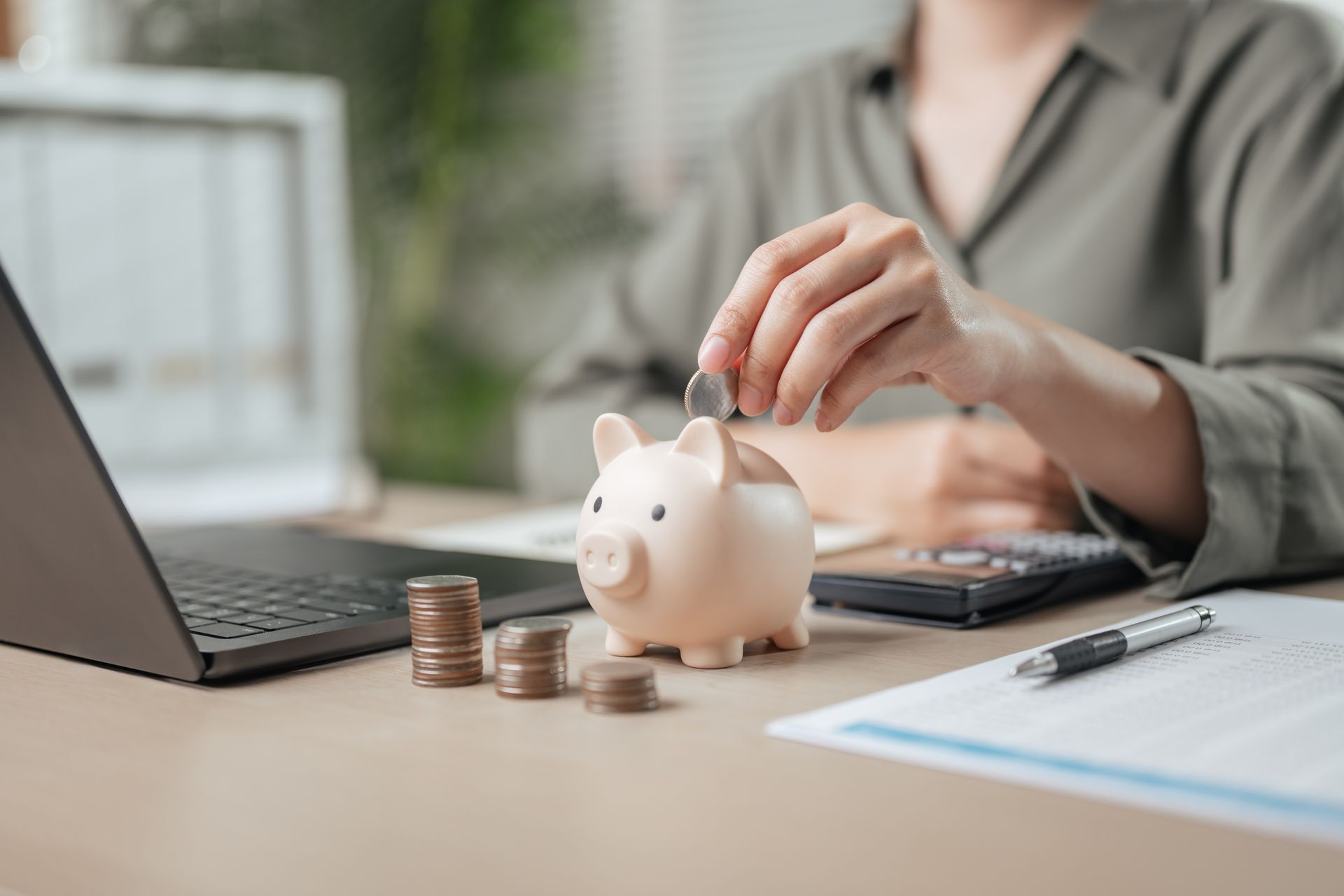 A woman is putting coins into a piggy bank.