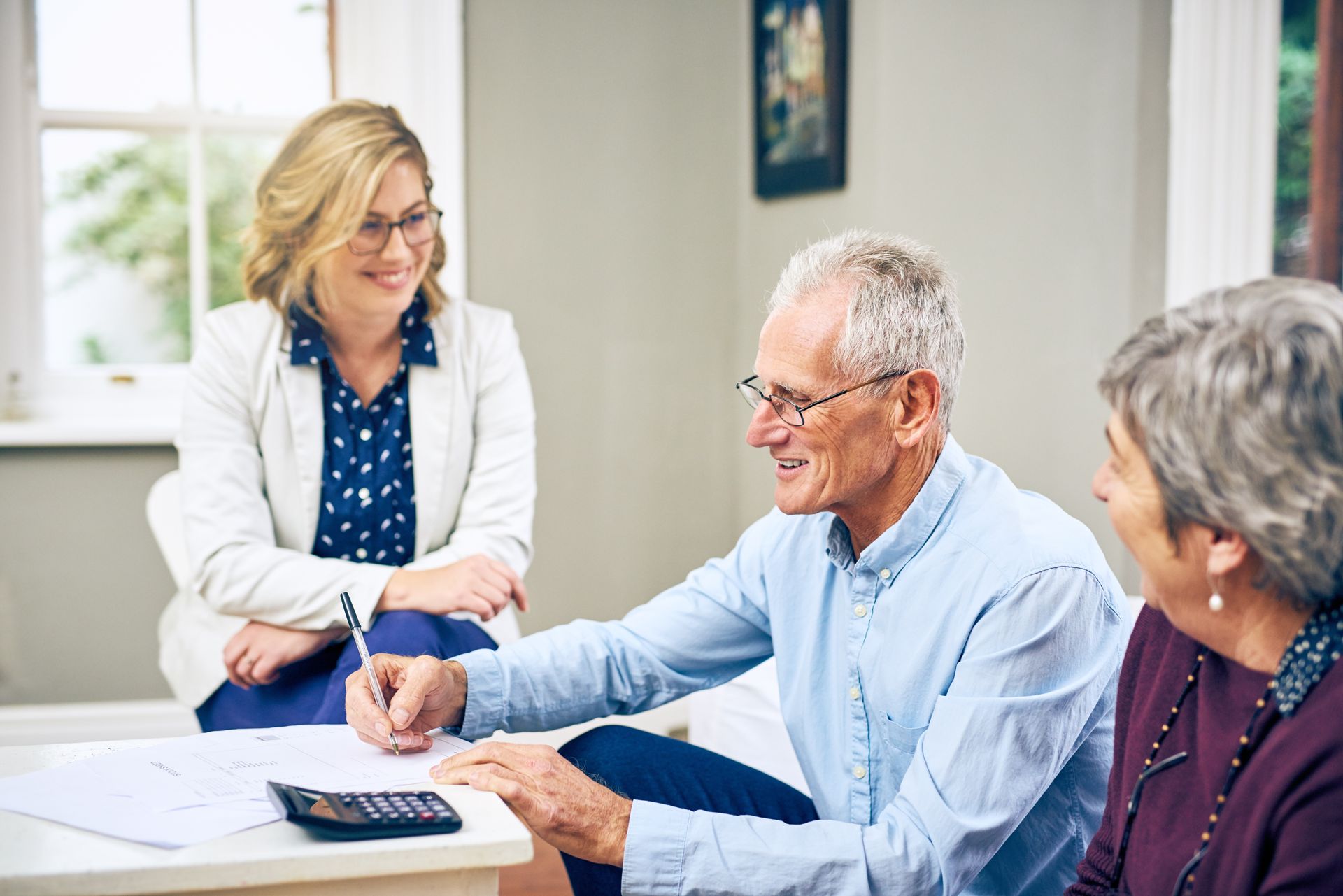 An elderly couple is sitting at a table with a woman.