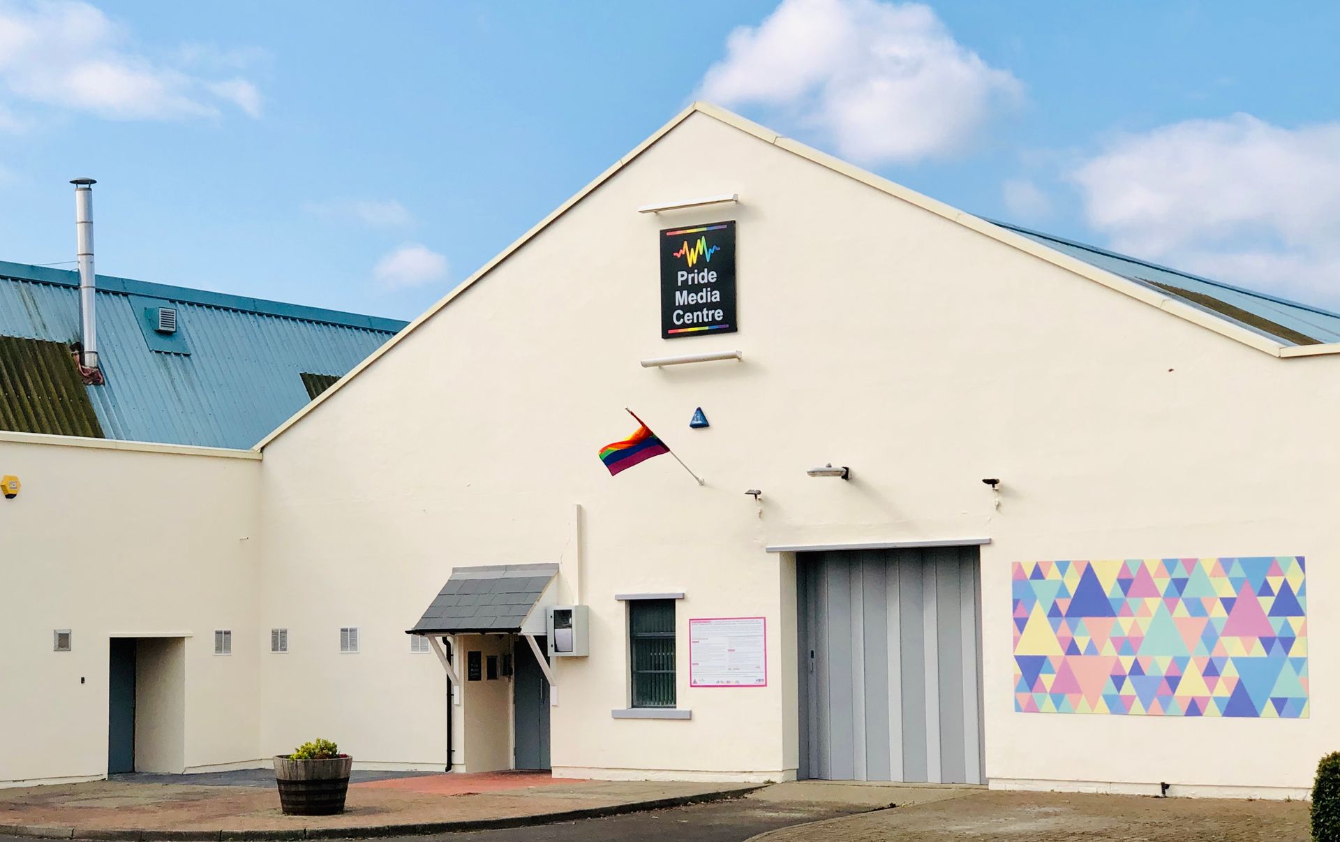 A white building with a rainbow flag on the side