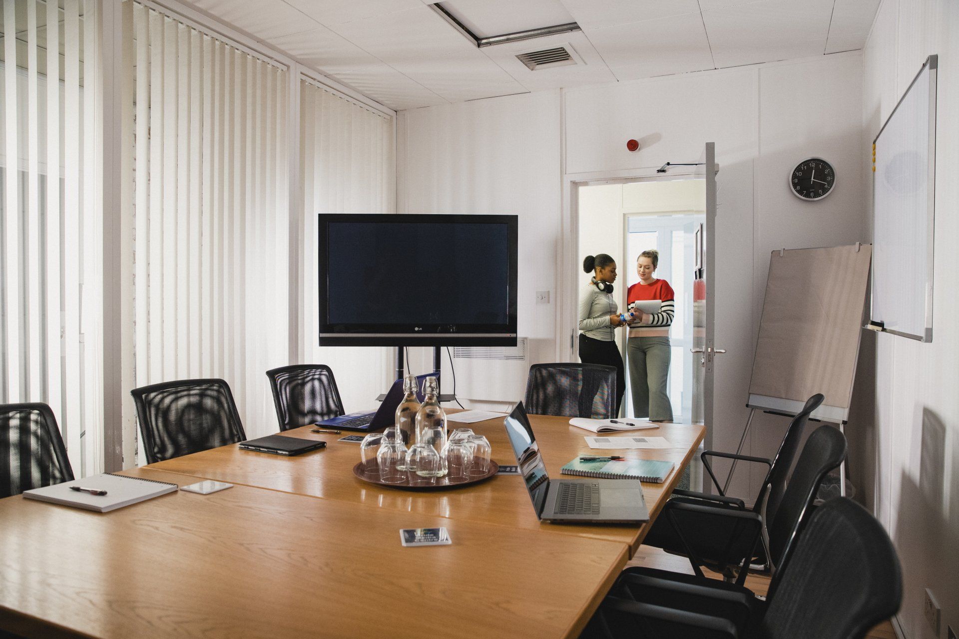 A conference room with a long table and chairs and a flat screen tv.