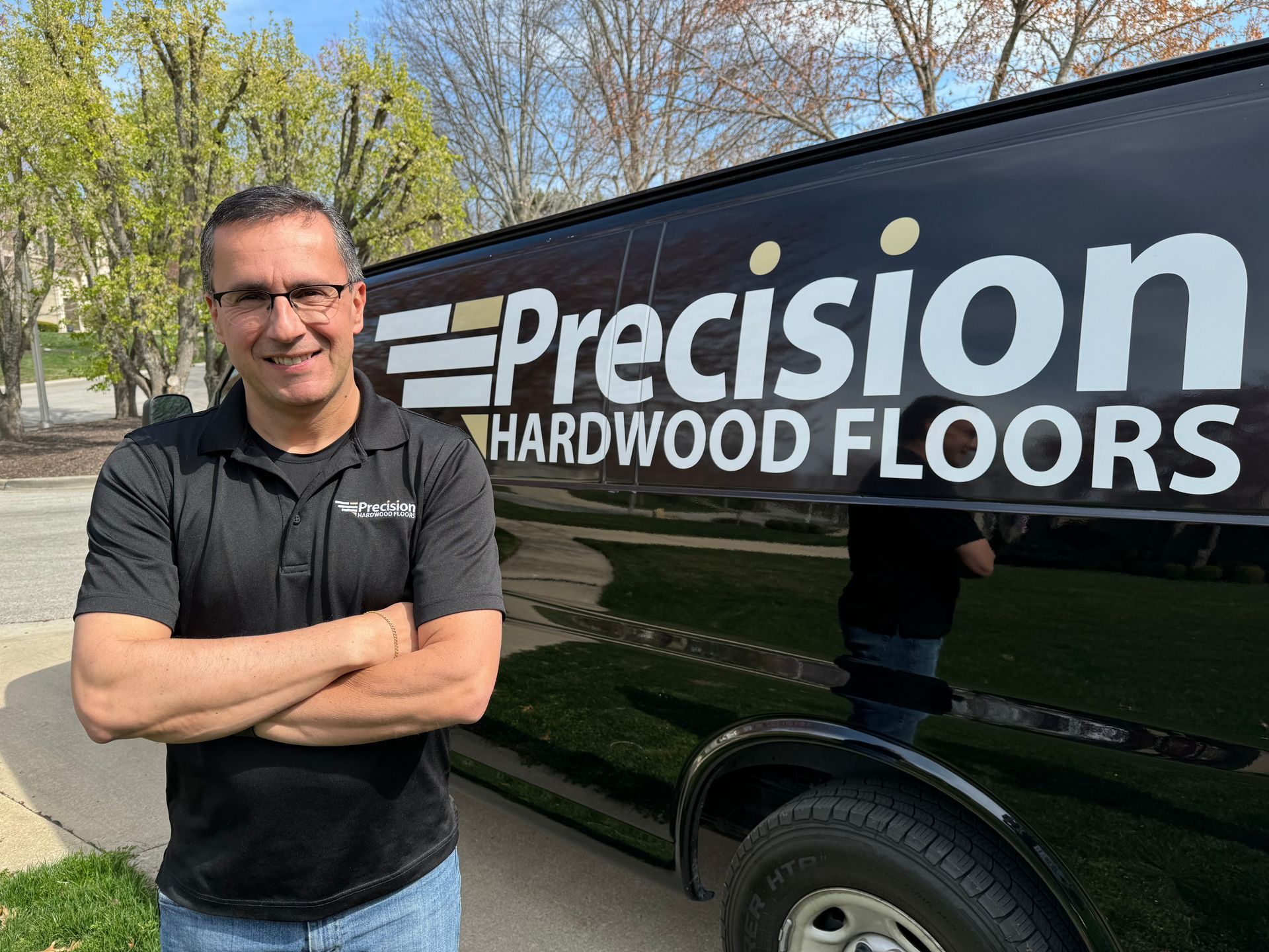 Cris Barbosa is standing in front of a precision hardwood floors van.