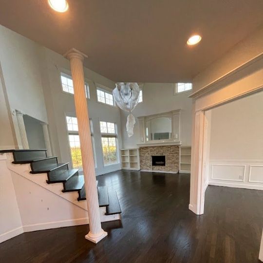An empty living room with stairs and a fireplace