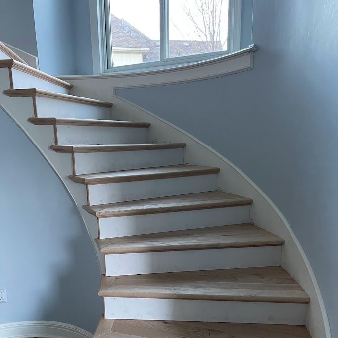 A curved staircase with white steps and wooden steps