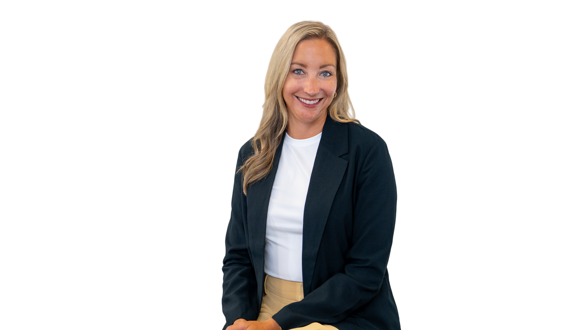 Woman with blonde hair smiles, wearing a gray vest over a white sweater, arms crossed.