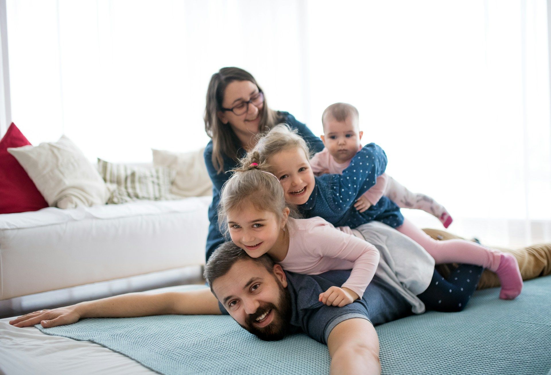 A smiling family of five playfully piled on top of each other on a bed.