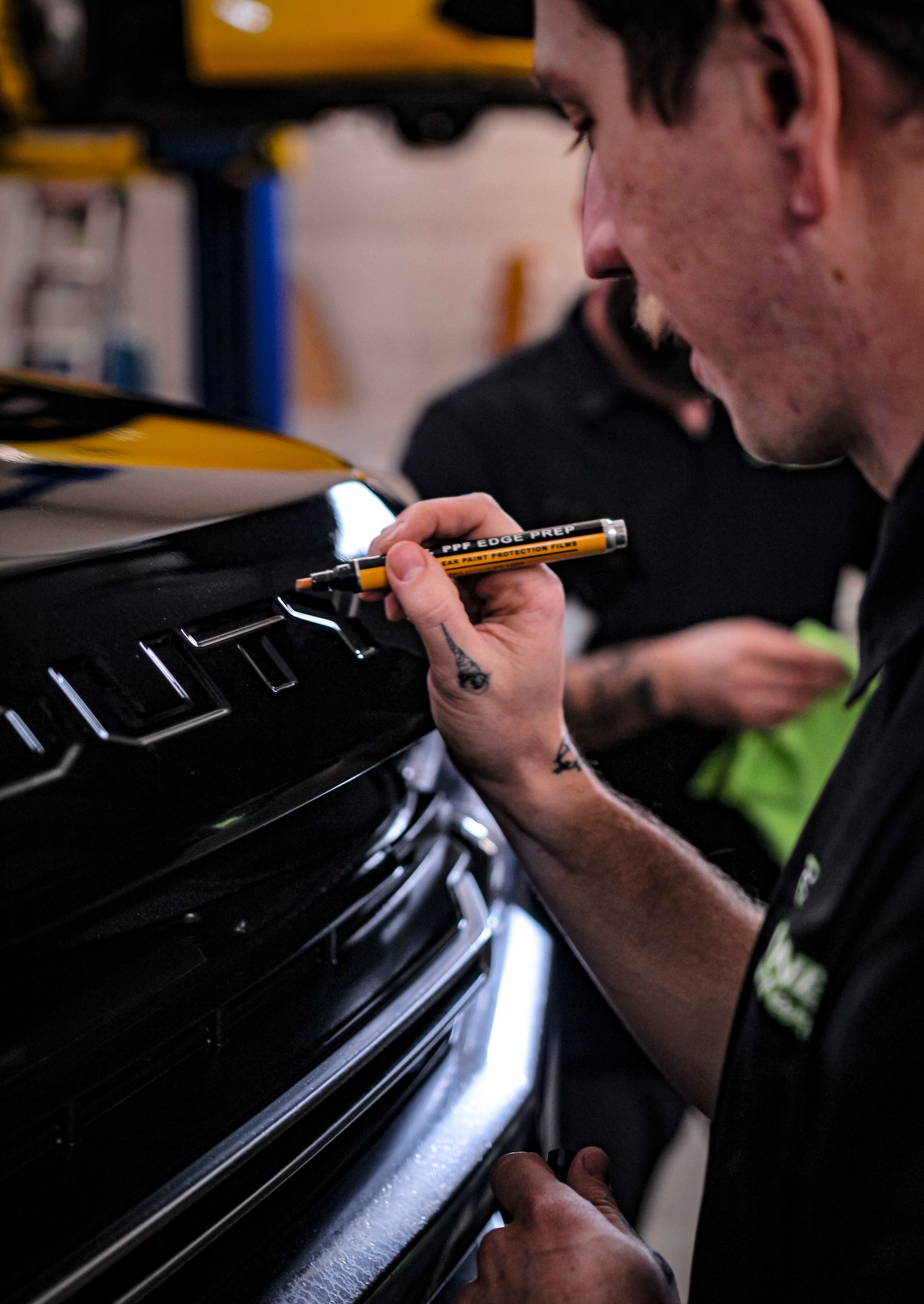 Person applying tinted film to a car window in a garage