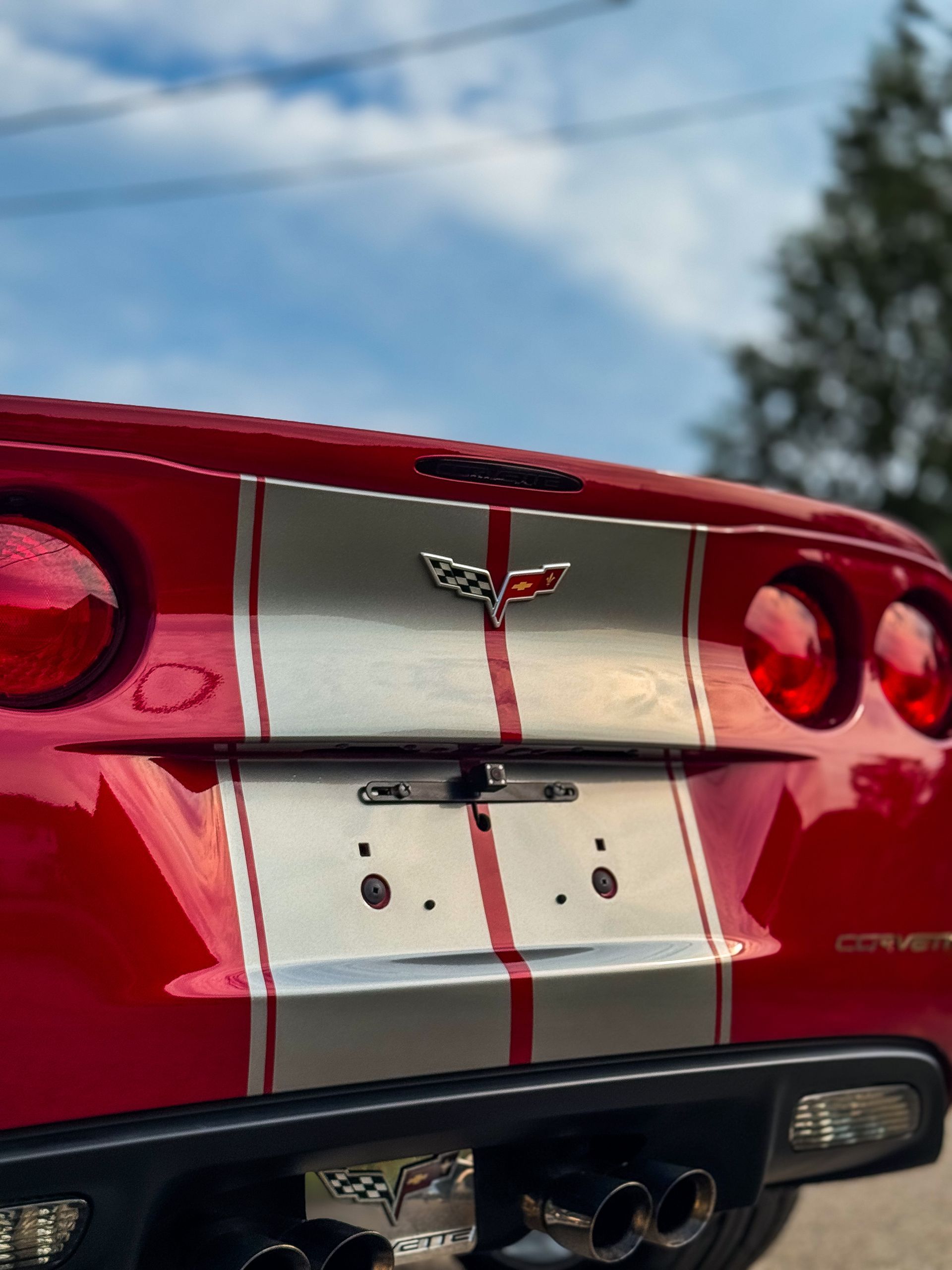 Red Corvette rear with silver racing stripes and Corvette logo.