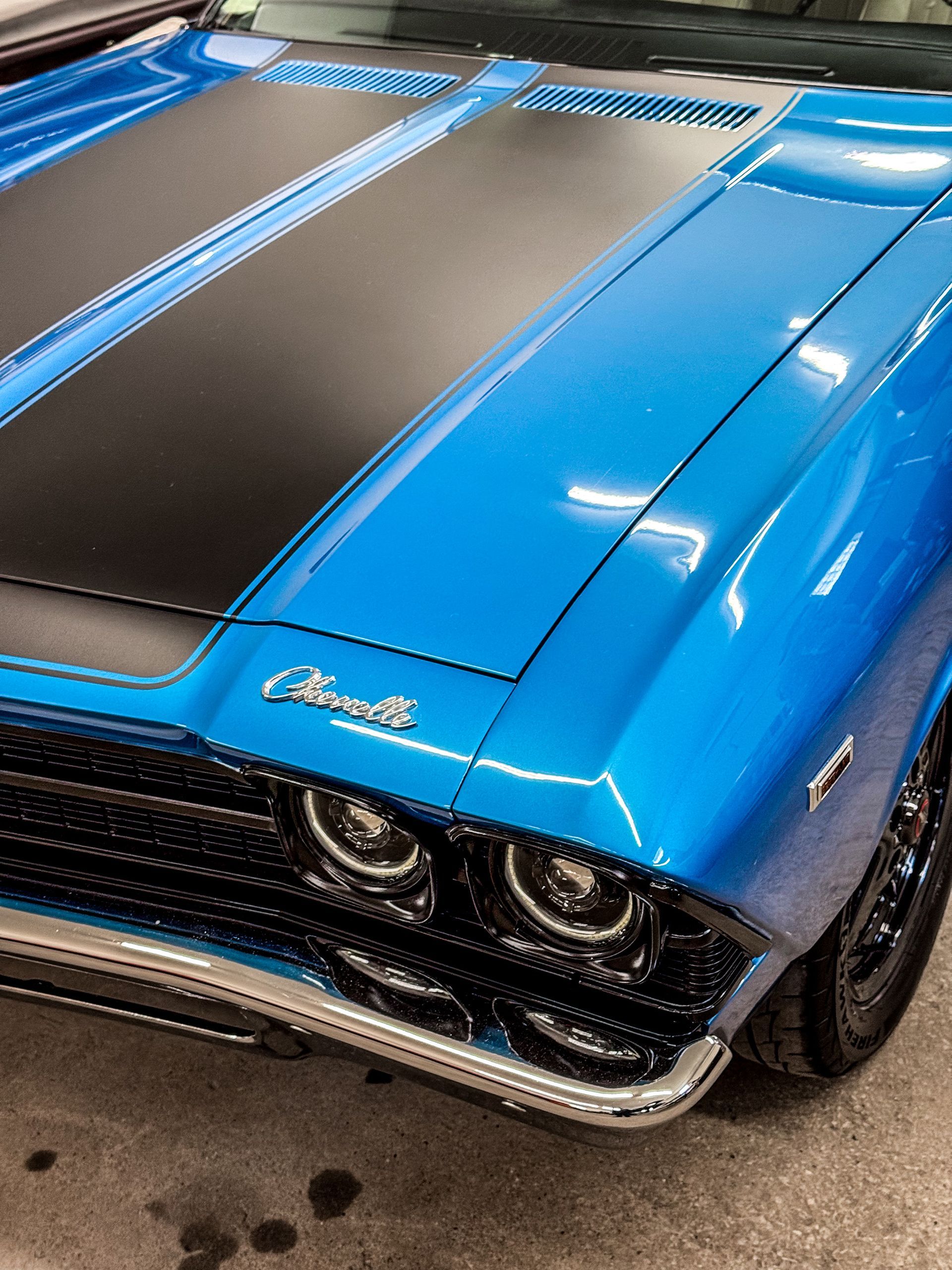 Blue classic Chevrolet Chevelle with black stripe on hood.