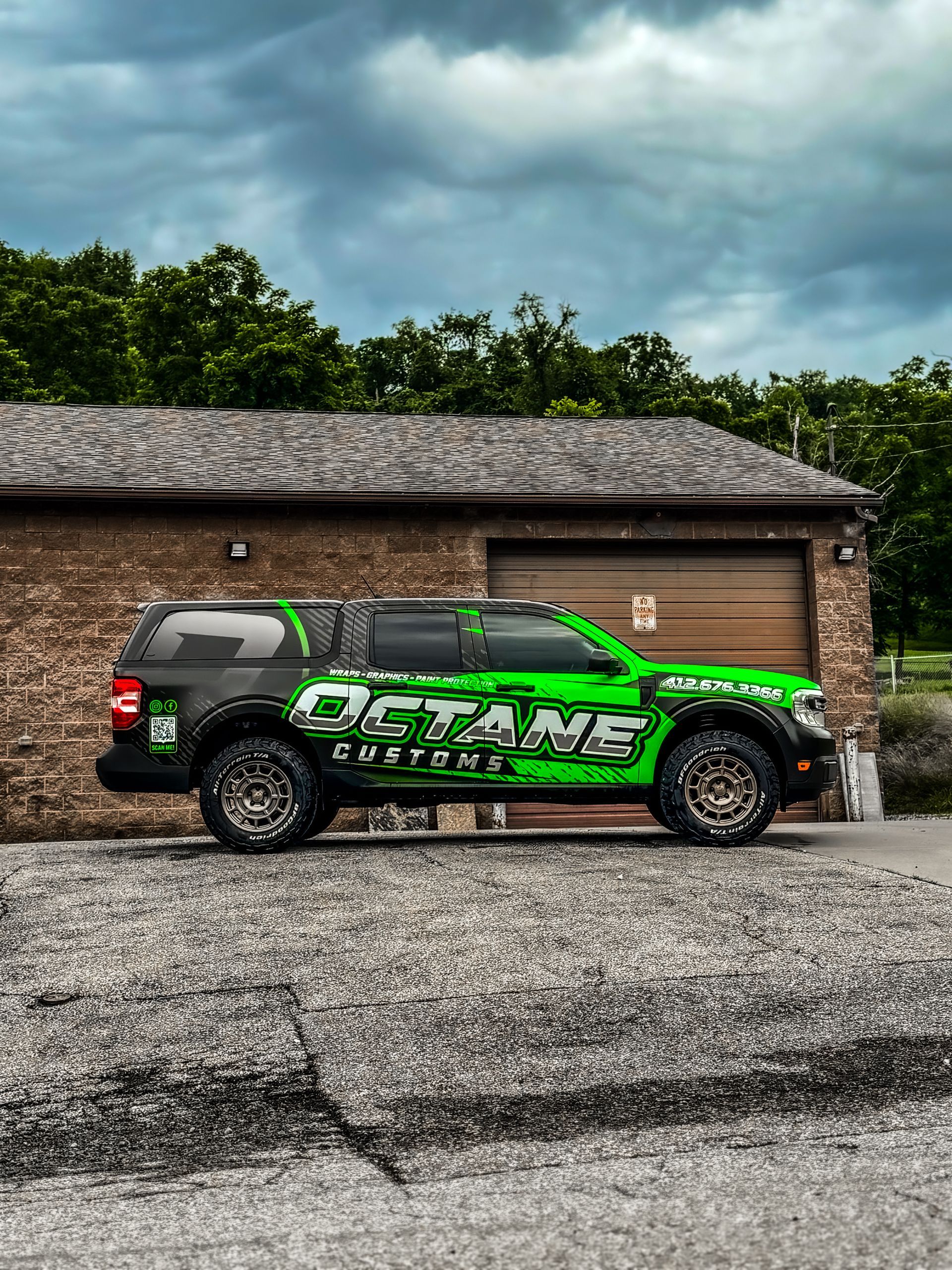Green and black Octane Customs truck parked outside a brick building.