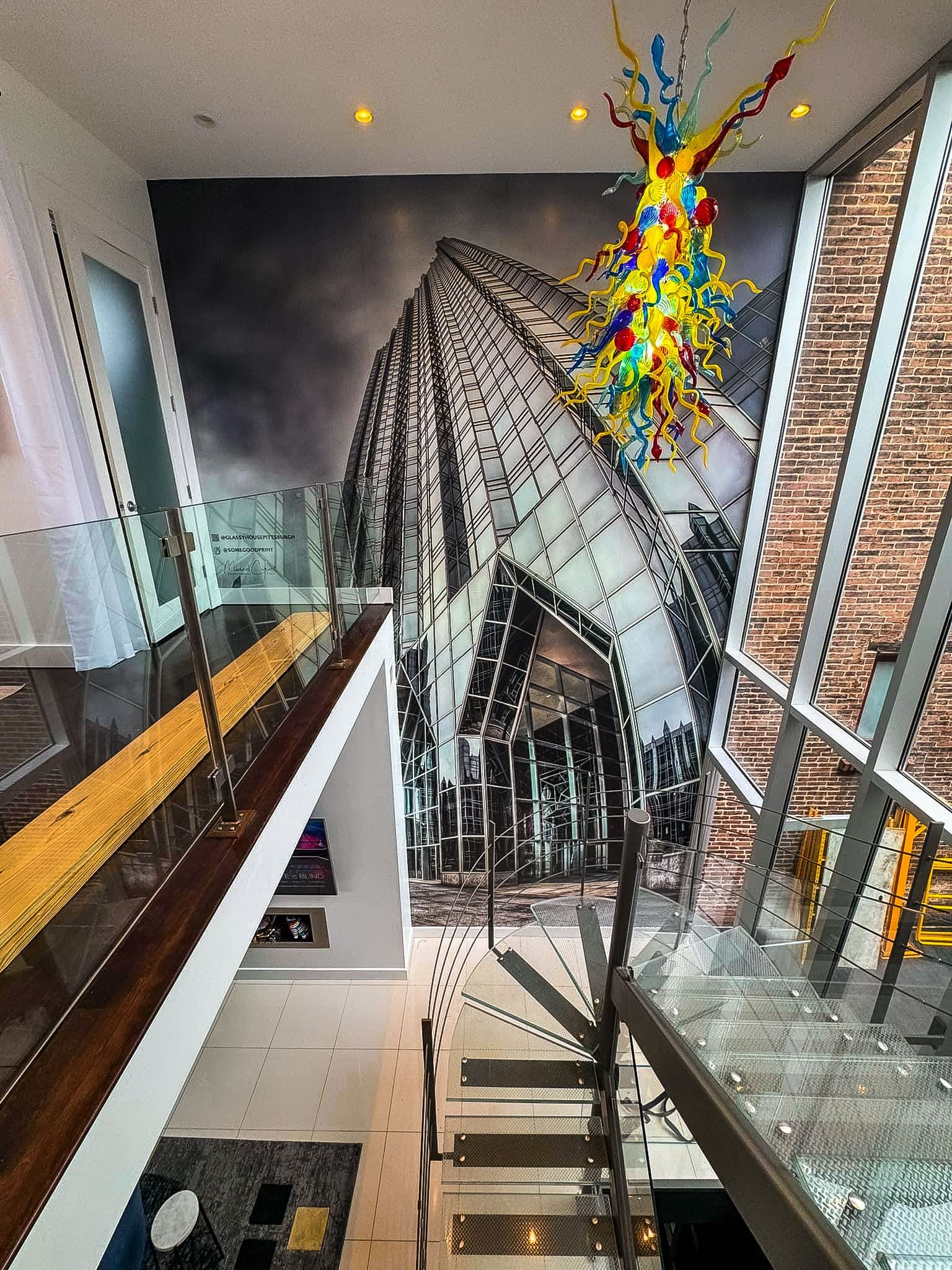 Modern interior with a large architectural mural, glass railings, and a colorful art installation.