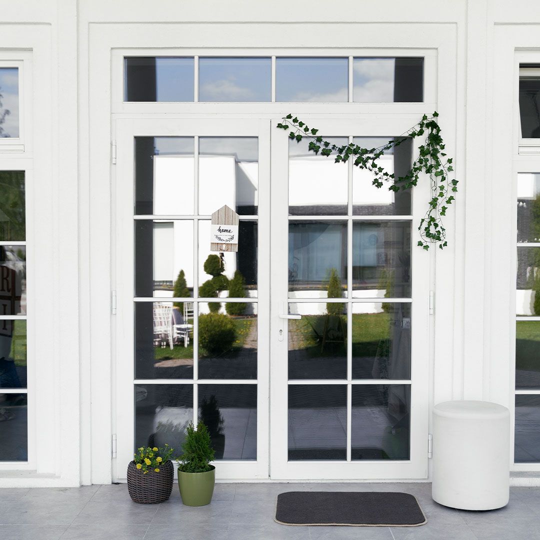 White French doors with glass panes, greenery, and small potted plants.