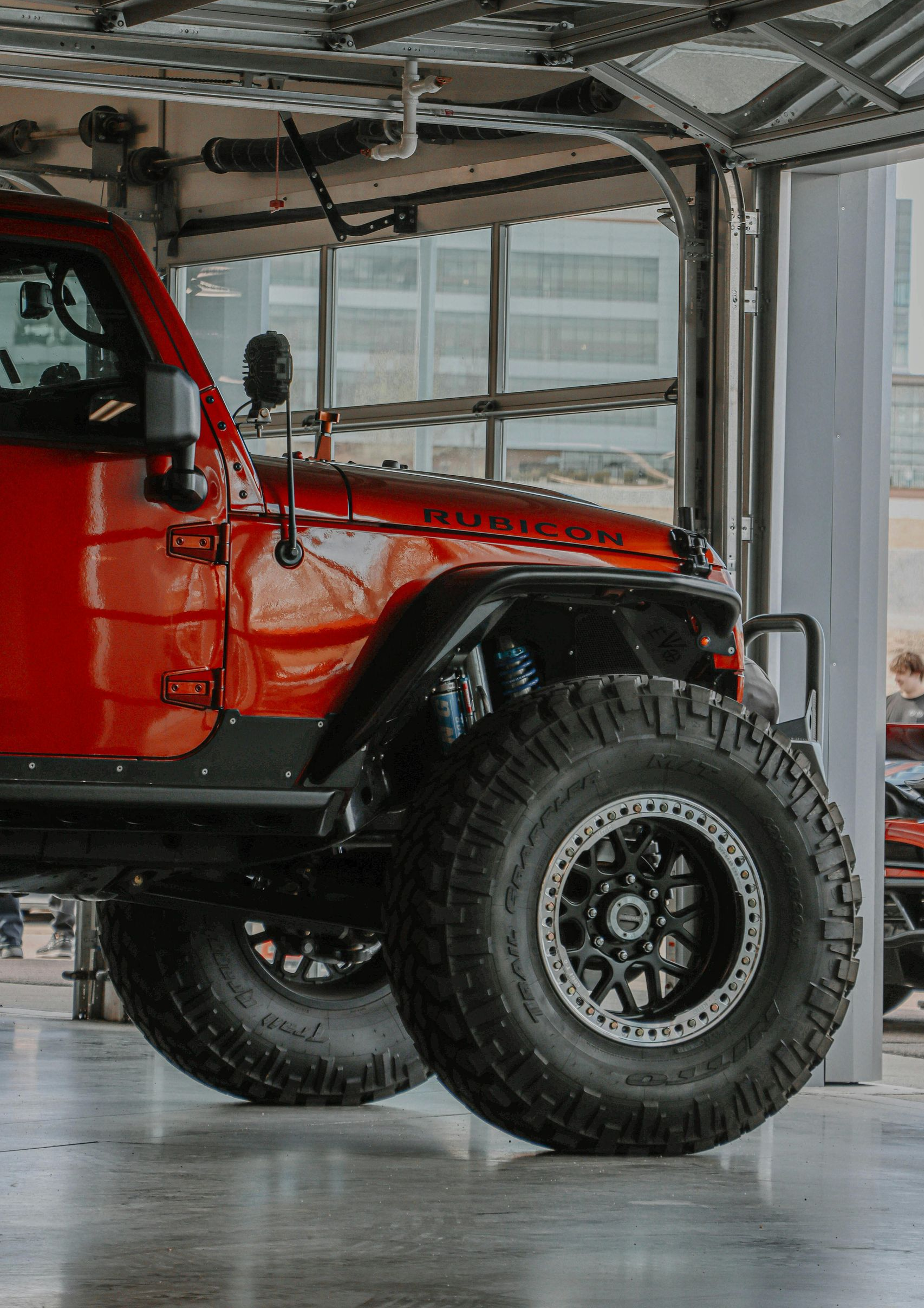 Red Jeep with large tires in a garage.
