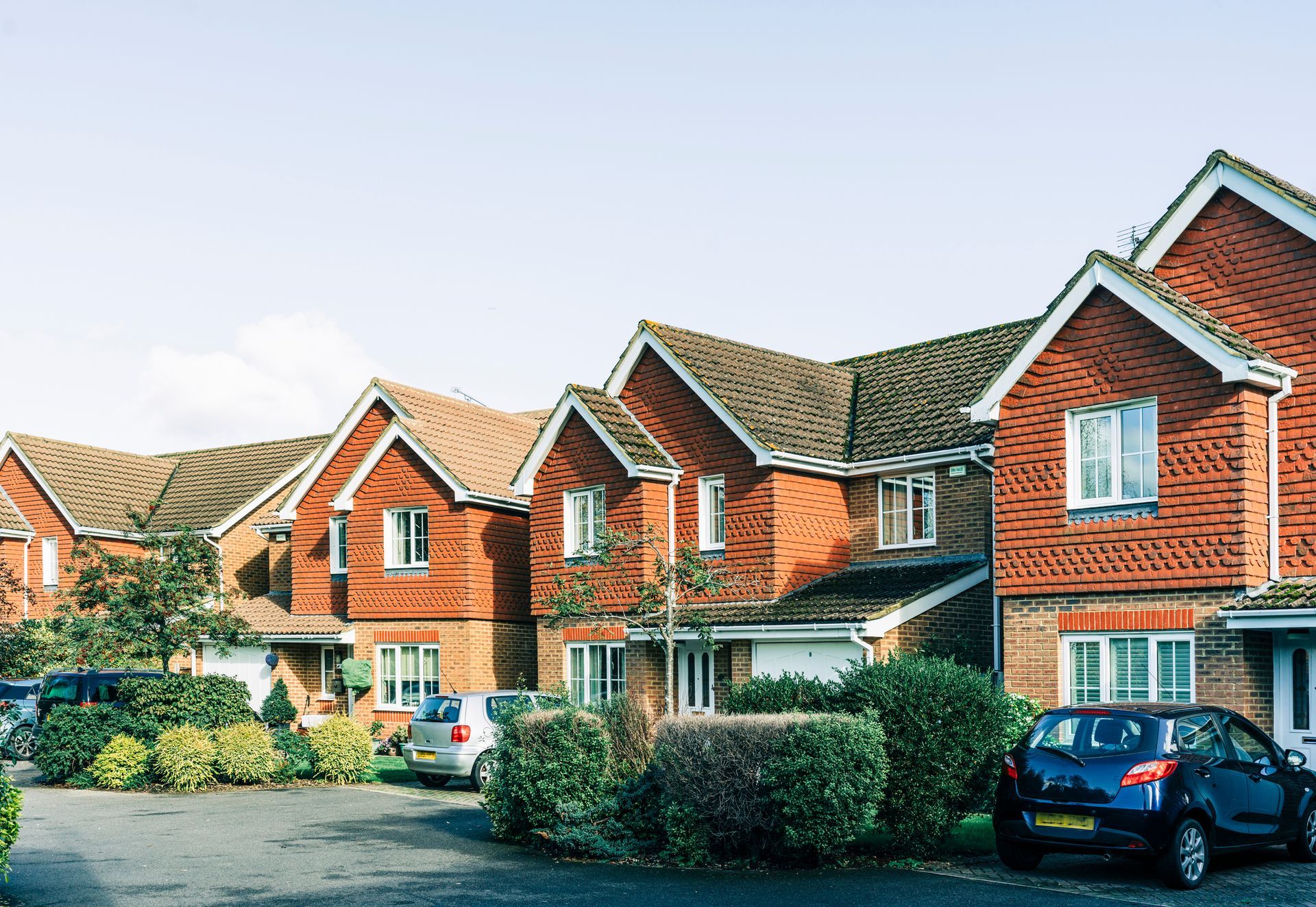 A row of brick houses with cars parked in front of them