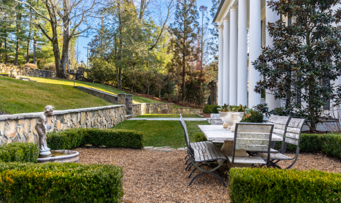 There is a table and chairs in the backyard of a house.