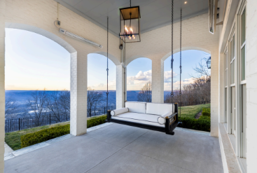 A porch with a swing and a couch hanging from the ceiling.