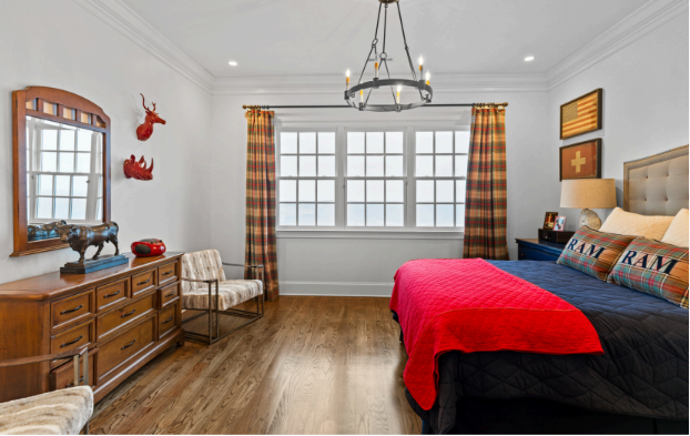 A bedroom with a bed , dresser , chair and mirror.