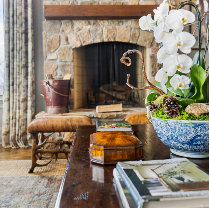 A living room with a fireplace and flowers on the table