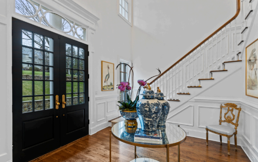 A hallway with a staircase and a table with a vase of flowers on it.