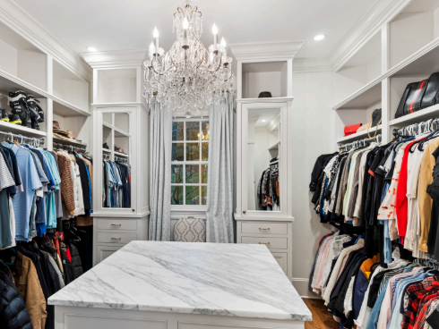 A walk in closet filled with lots of clothes and a chandelier.