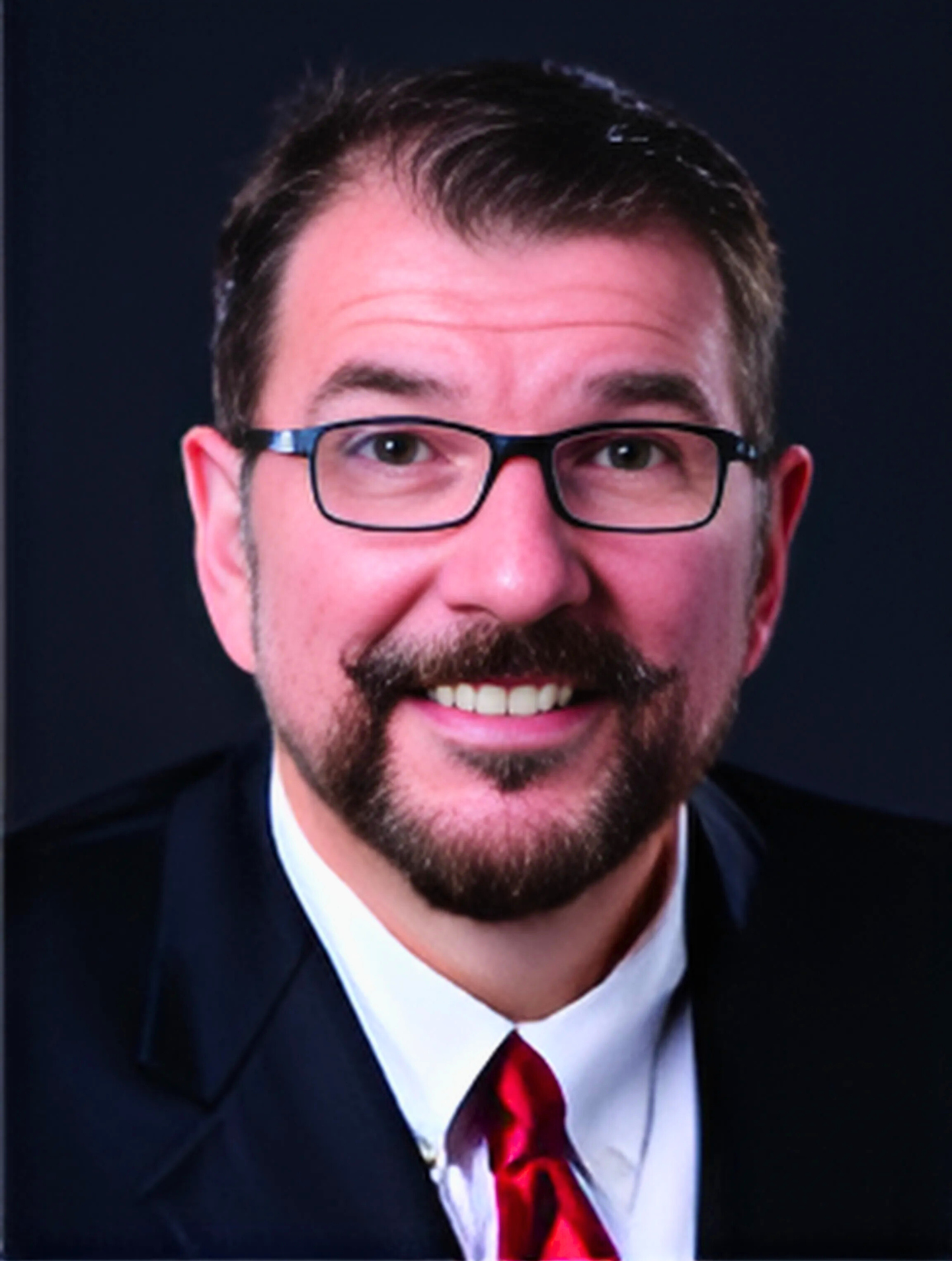 A man with glasses and a beard is smiling for the camera
