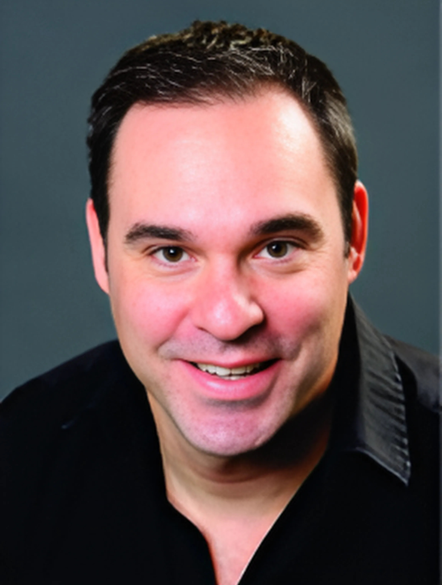 A man in a black shirt is smiling for the camera