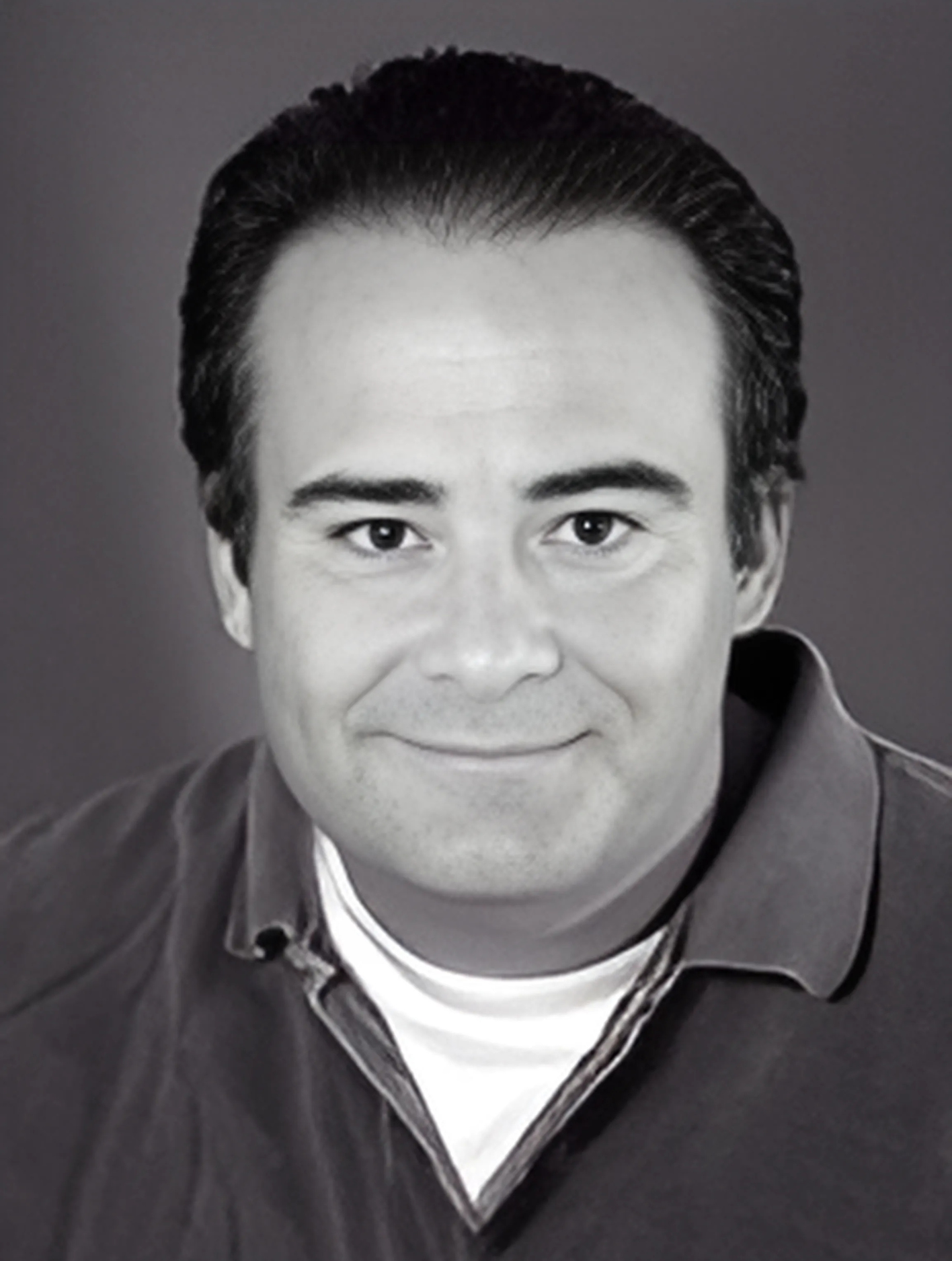 A black and white photo of a man wearing a polo shirt