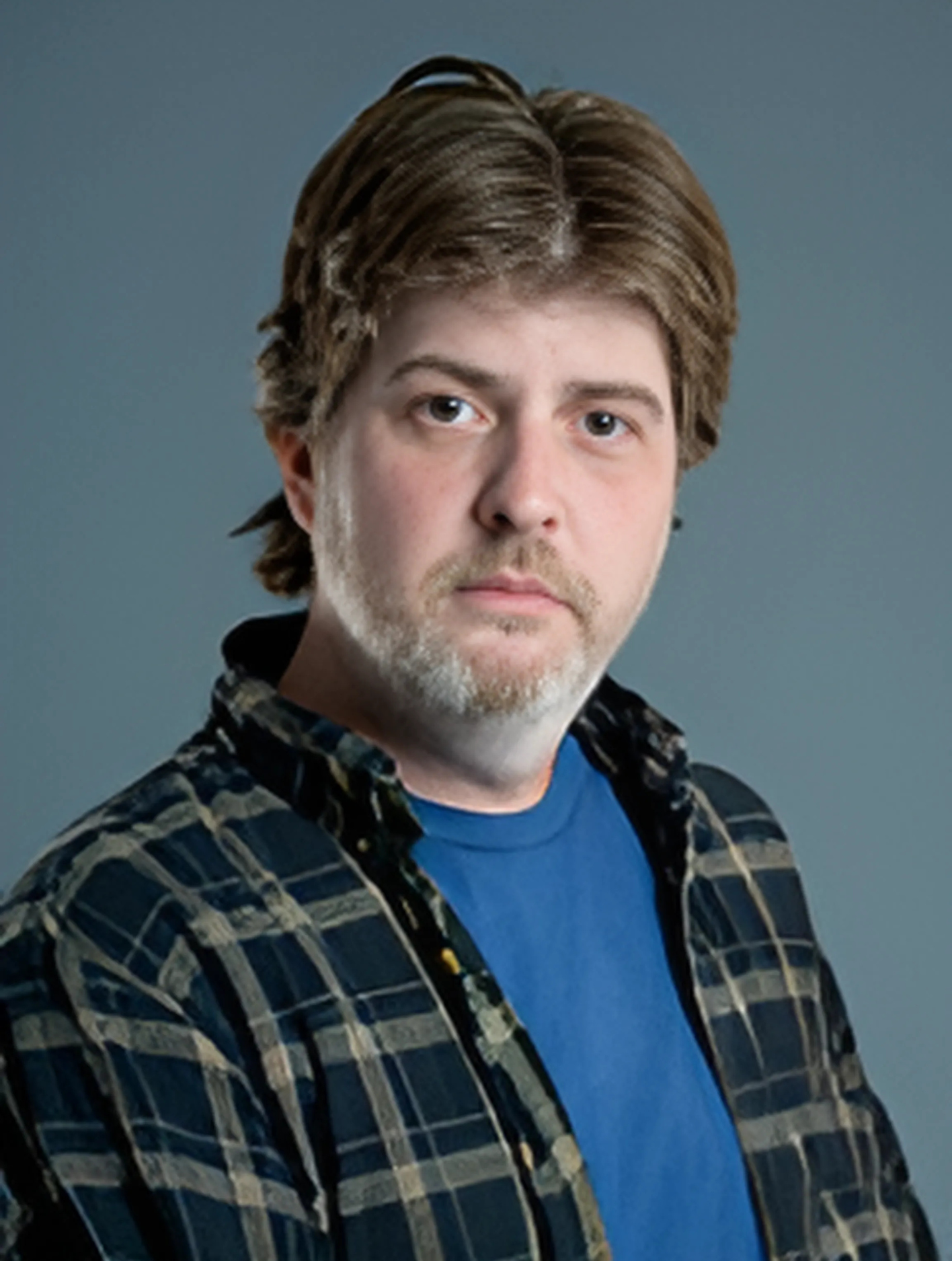 A man with a beard wearing a plaid shirt and a blue shirt