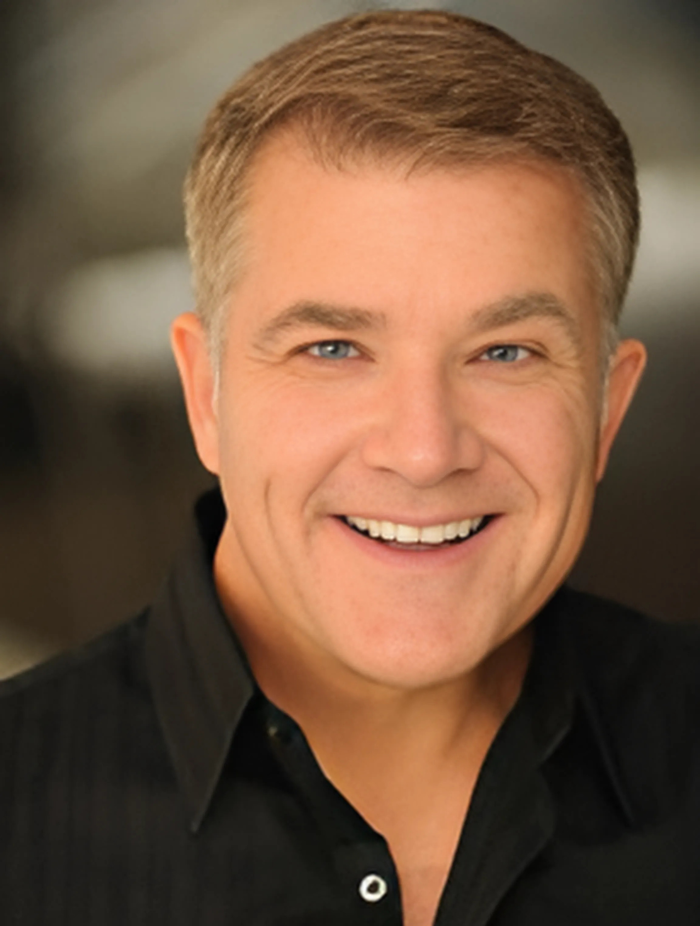 A man in a black shirt is smiling for the camera