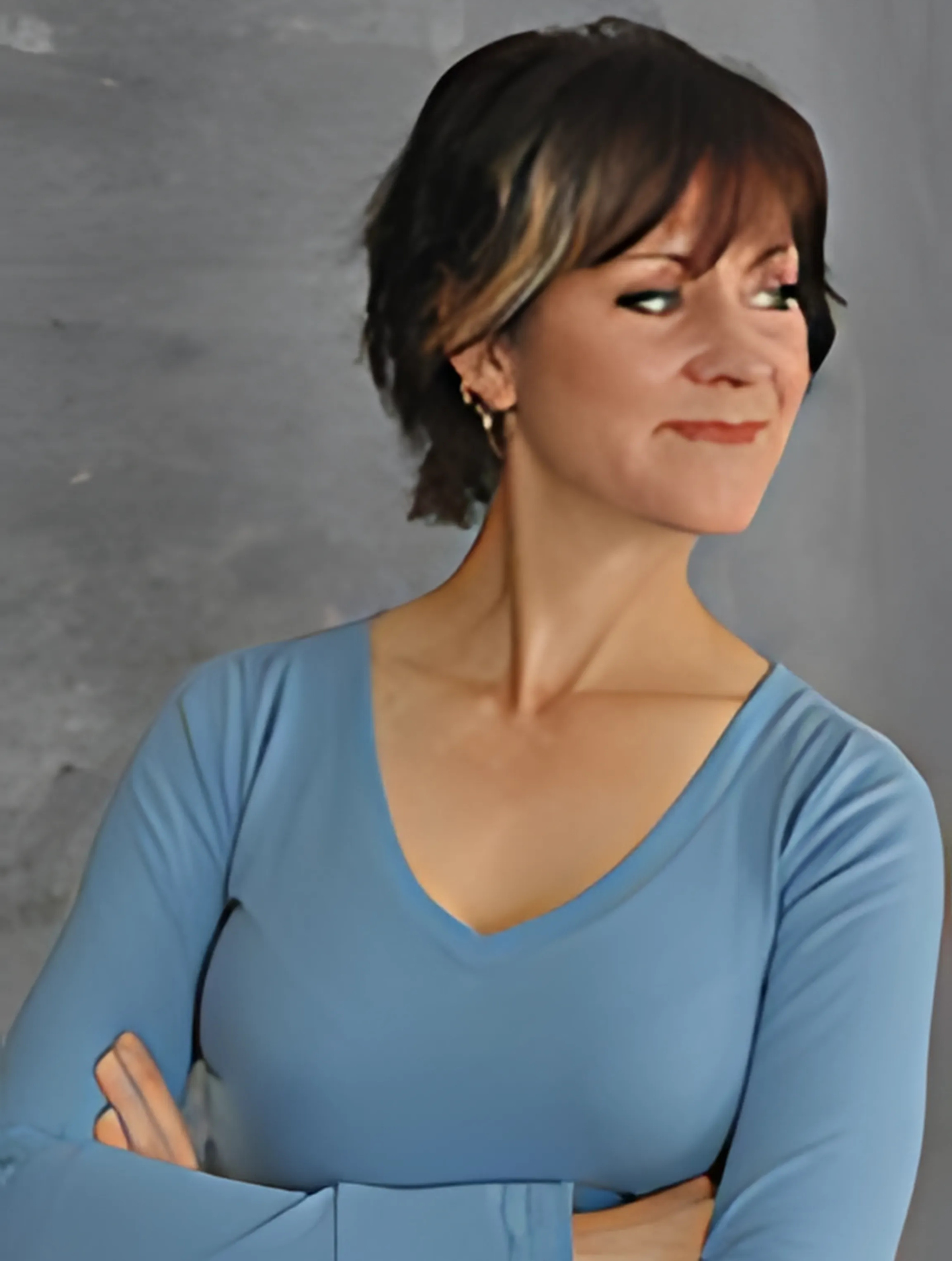 A woman in a blue shirt with her arms crossed