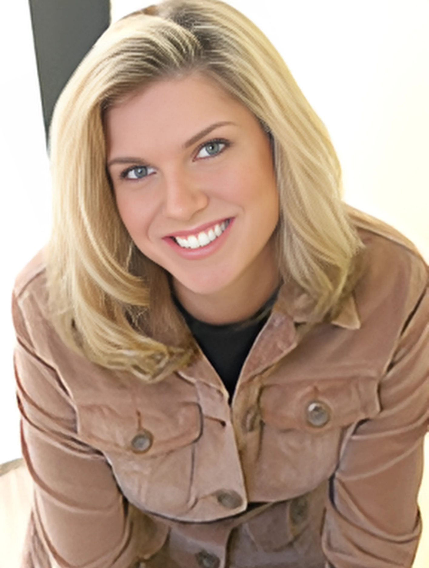 A woman in a brown jacket smiles for the camera