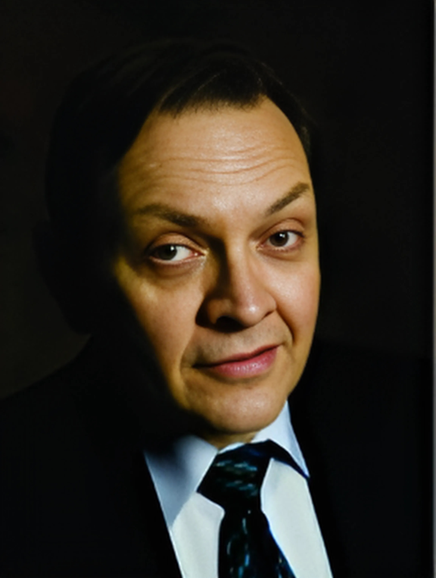 A man in a suit and tie looks at the camera