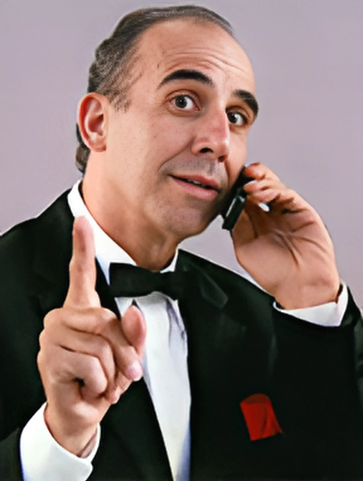A man in a tuxedo is talking on a cell phone