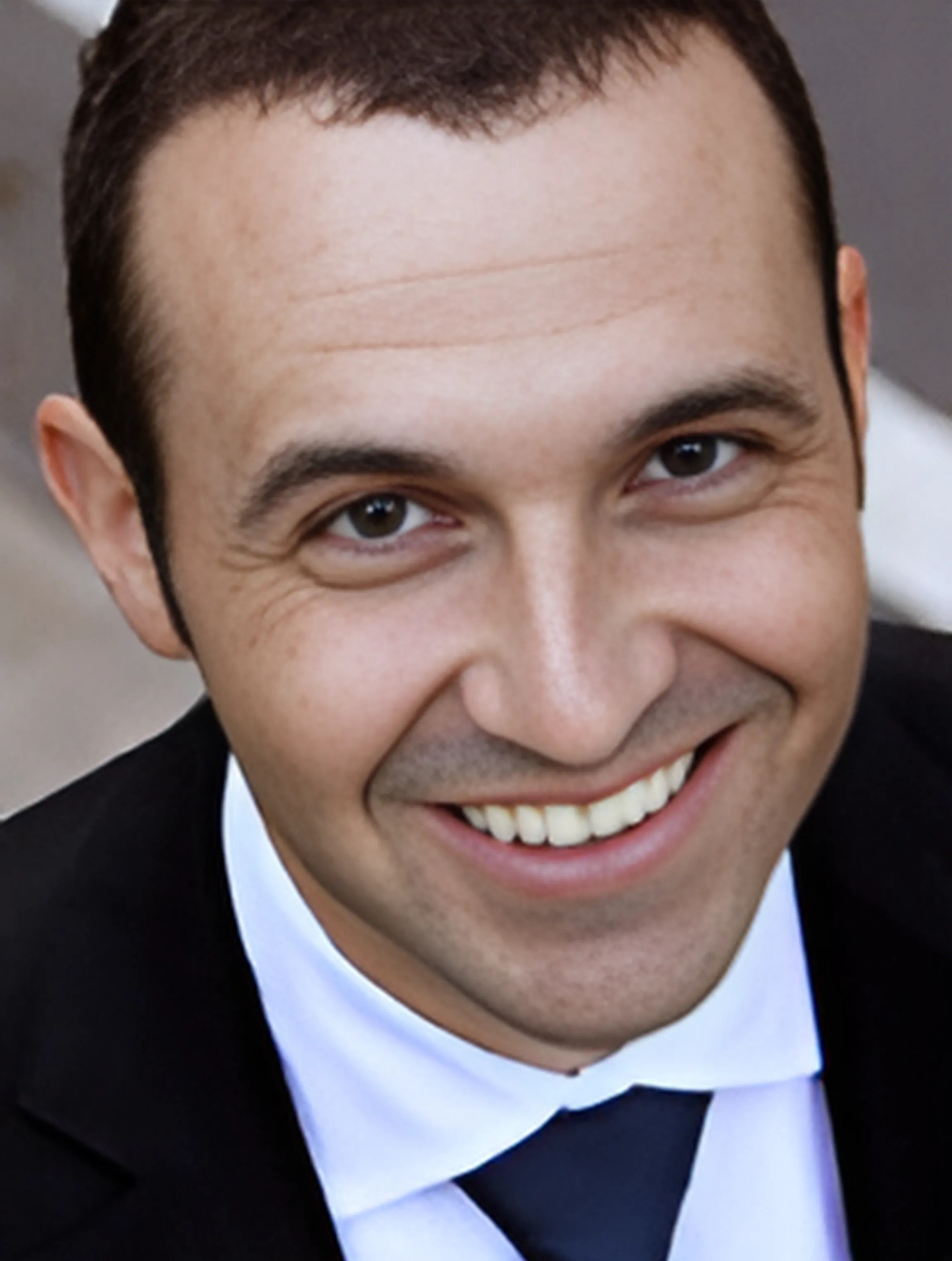 A man in a suit and tie is smiling for the camera