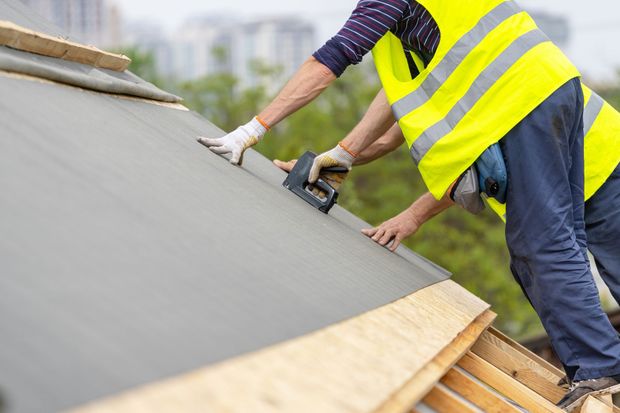 A man is installing solar panels on the roof of a house
