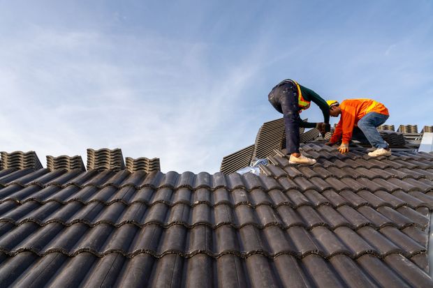 A man is working on a roof with a drill.