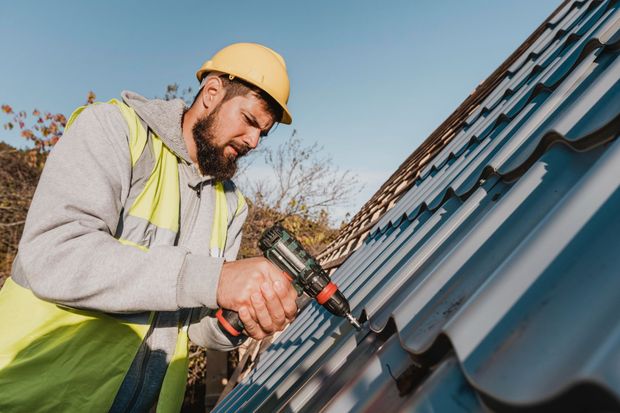 Two men are working on a roof of a house.