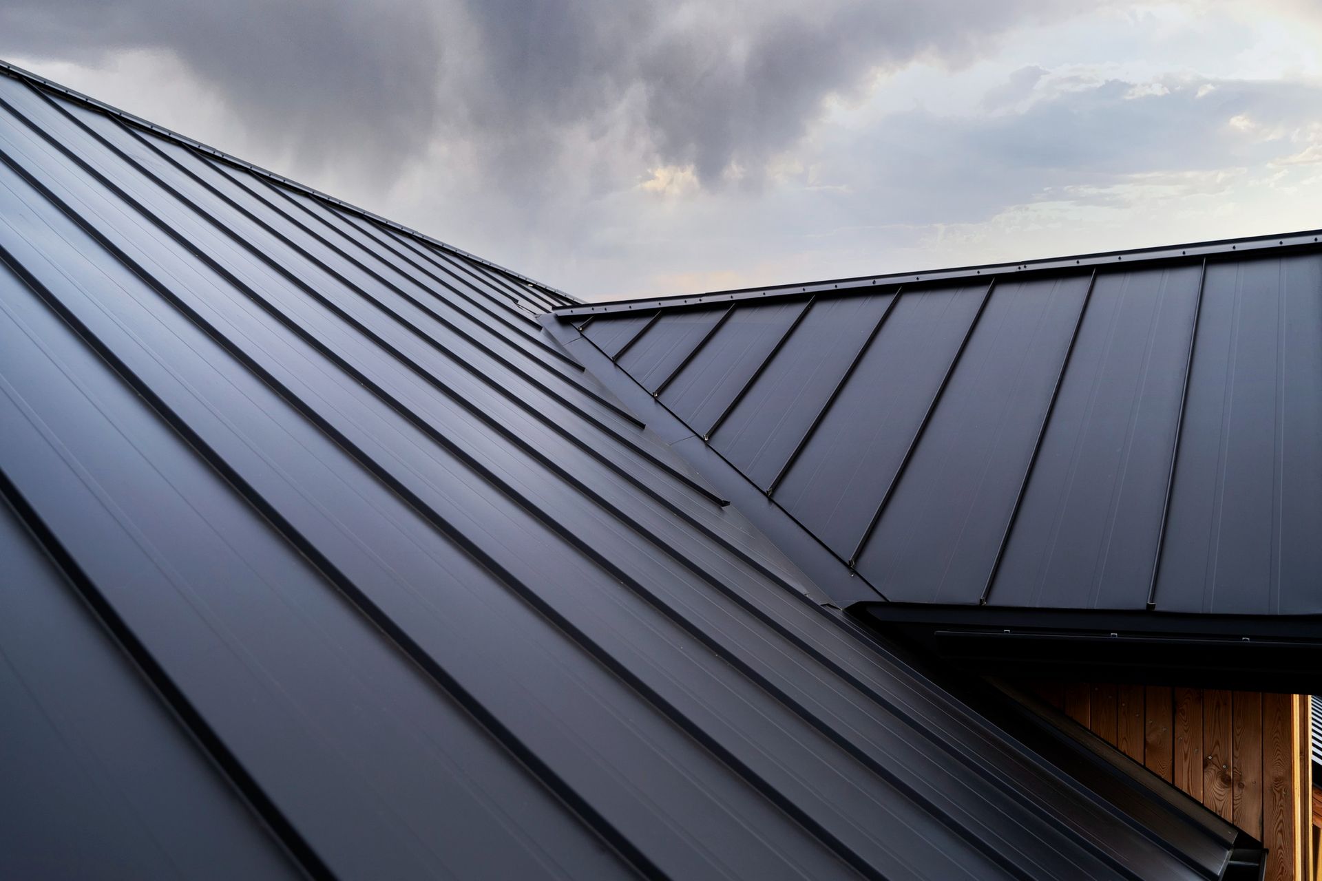 A close up of a black roof with a cloudy sky in the background.