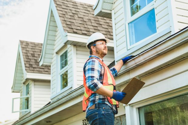 Two men are working on the roof of a wooden house.
