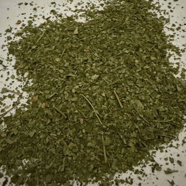 Dried, Chopped Green Leaves, Possibly Herbs Or Spices, Scattered On A White Surface — Atherton Health Food Centre in Atherton, QLD