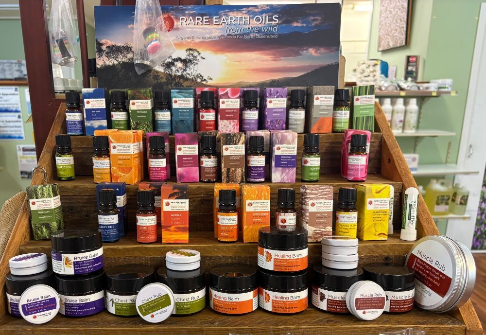 A display of essential oils and body products in a shop, arranged on a wooden shelf with a sunset background — Atherton Health Food Centre in Atherton, QLD