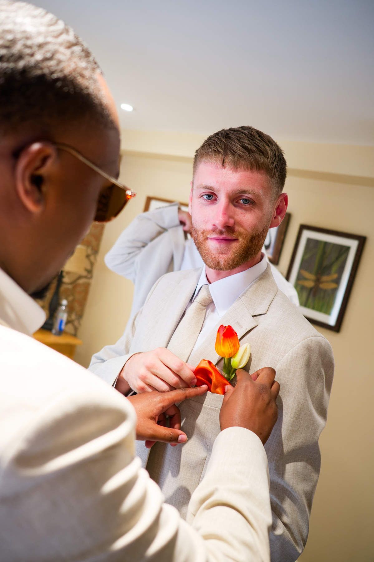 A man is putting a flower on another man 's jacket.