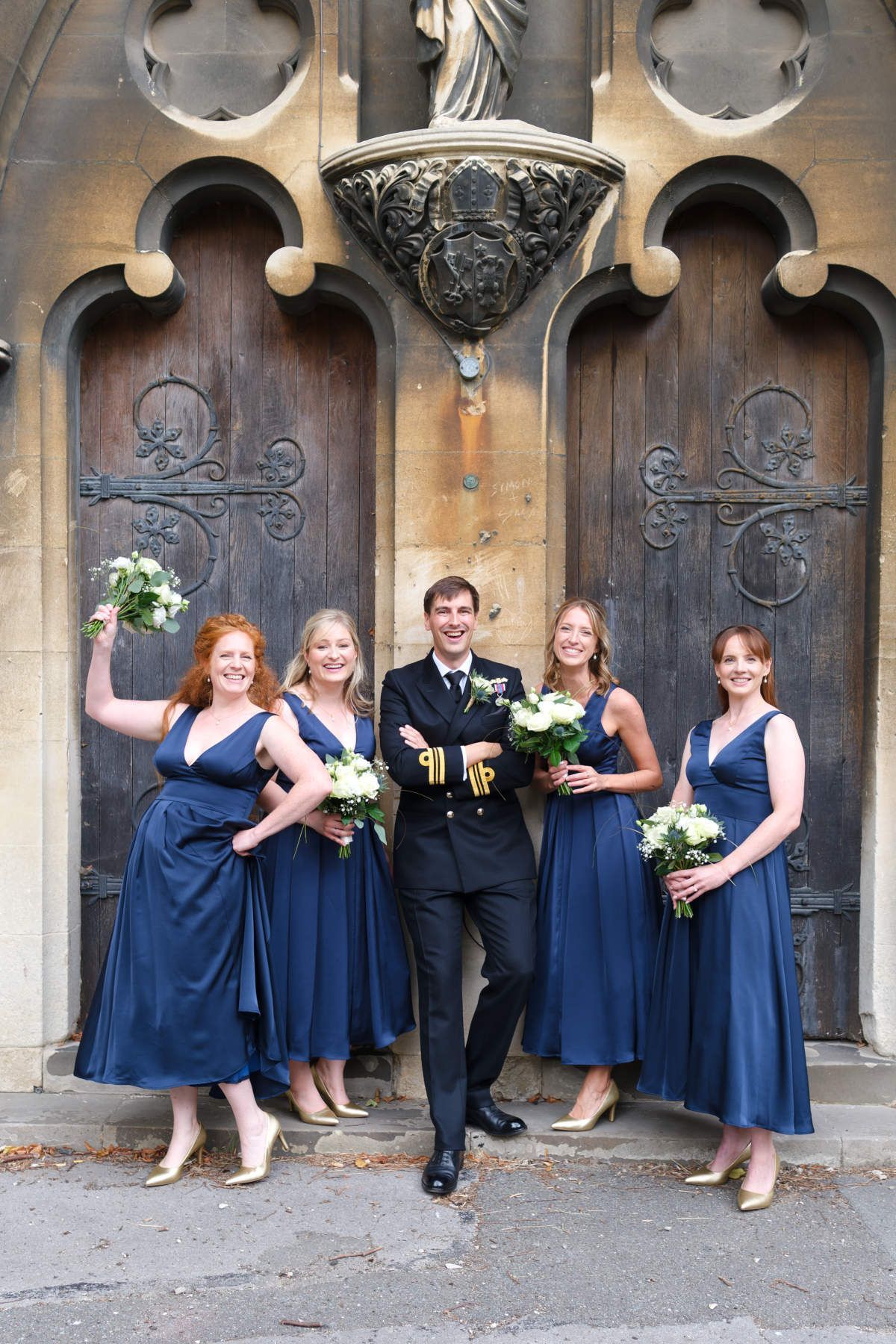 A bride and groom are posing for a picture with their bridesmaids in front of a church.