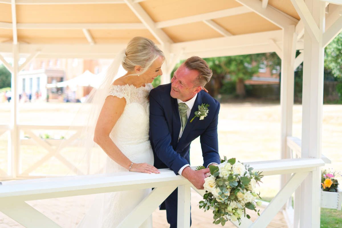 A bride and groom are posing for a picture in front of a gazebo.