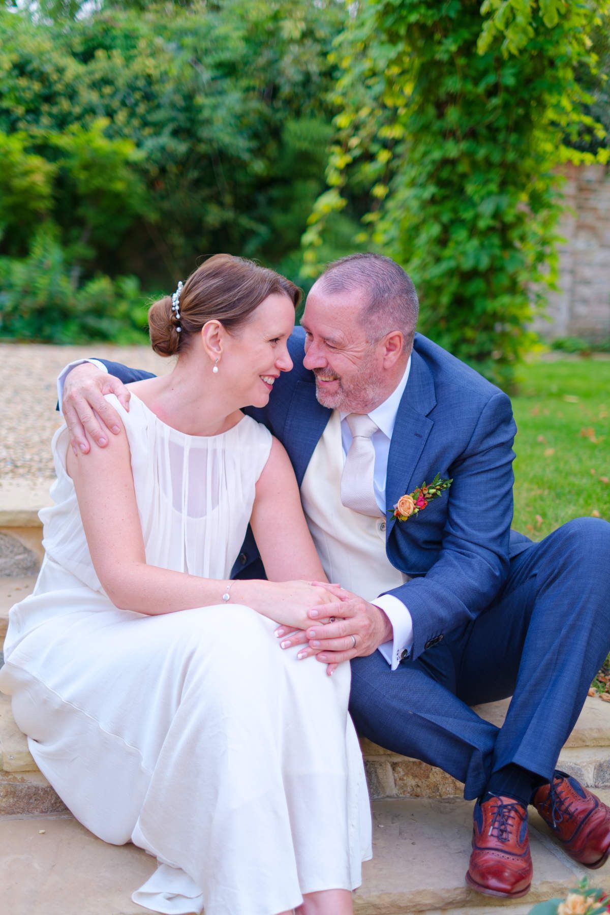 A bride and groom are sitting next to each other on a stone step.