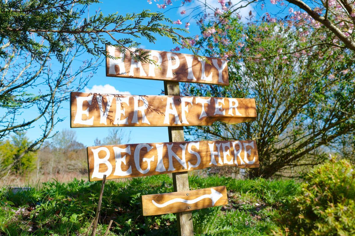 A wooden sign that says happily ever after begins here