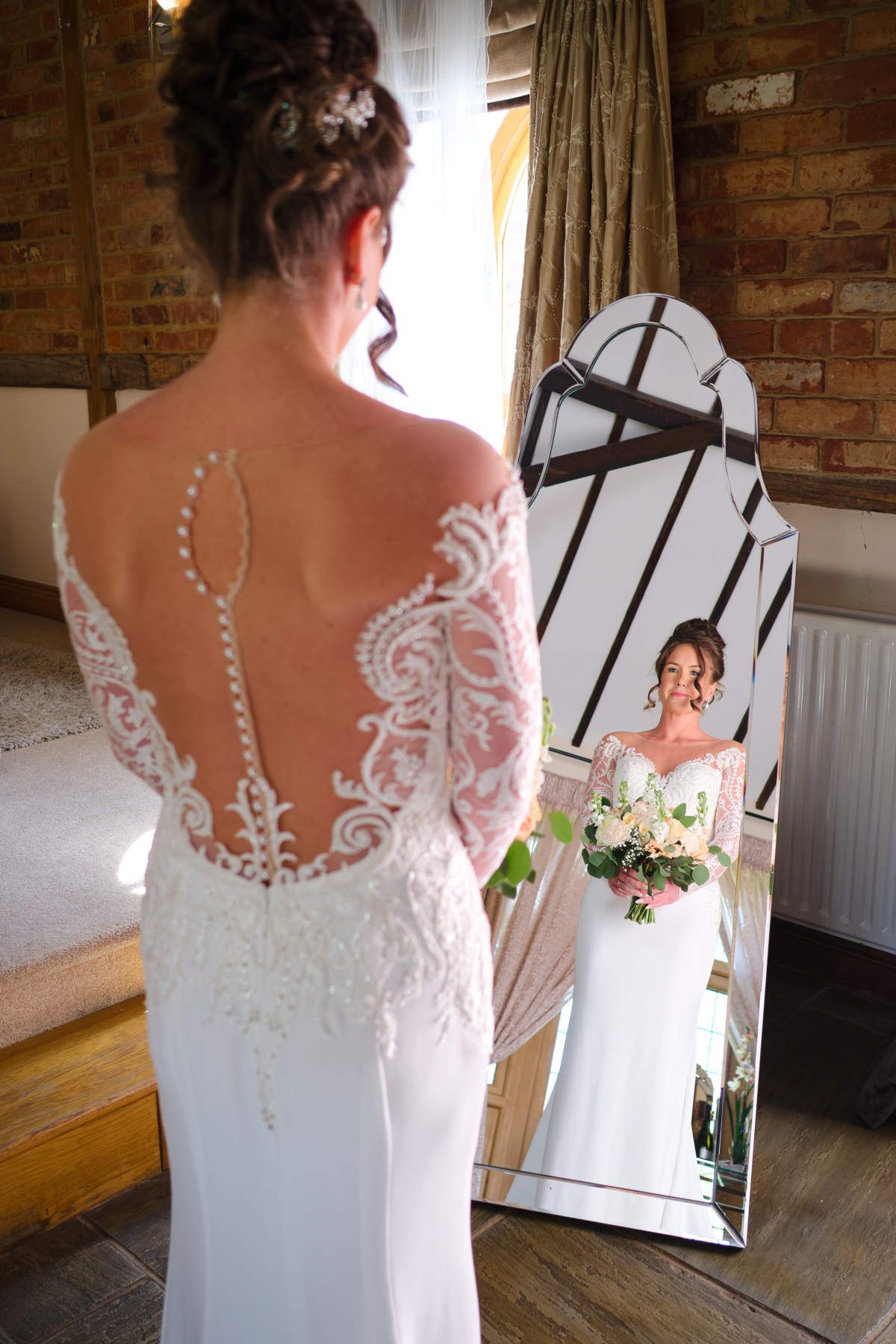 A woman in a wedding dress is standing in front of a mirror.