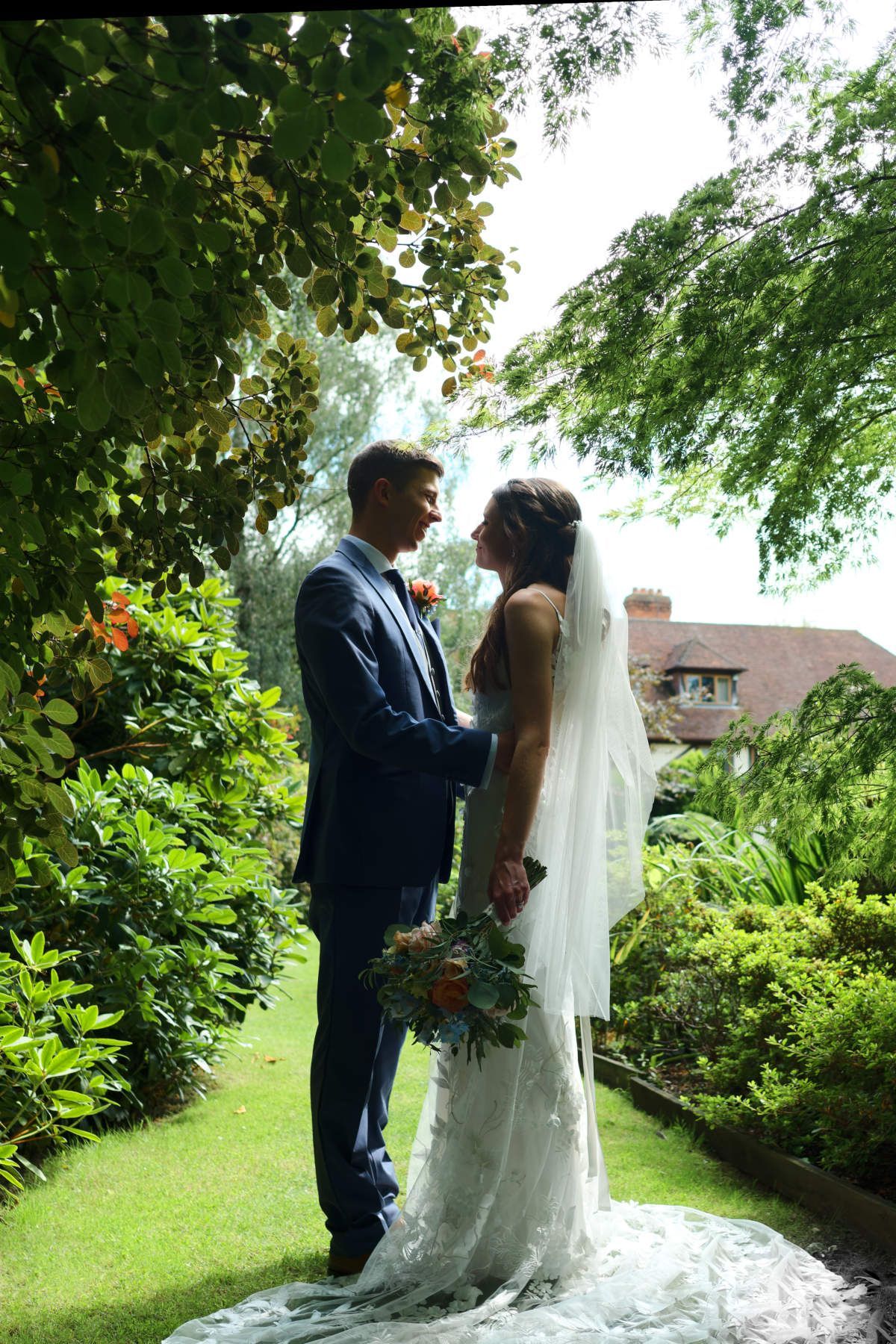 A bride and groom are kissing in front of a river in Hampshire.