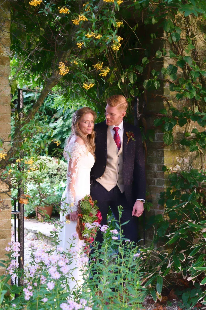 A bride and groom are standing next to each other in a garden.