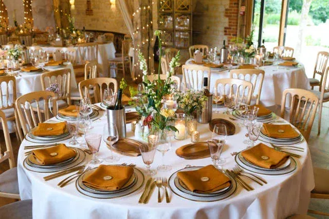 A table is set for a wedding reception with plates, utensils, and wedding flowers on it.